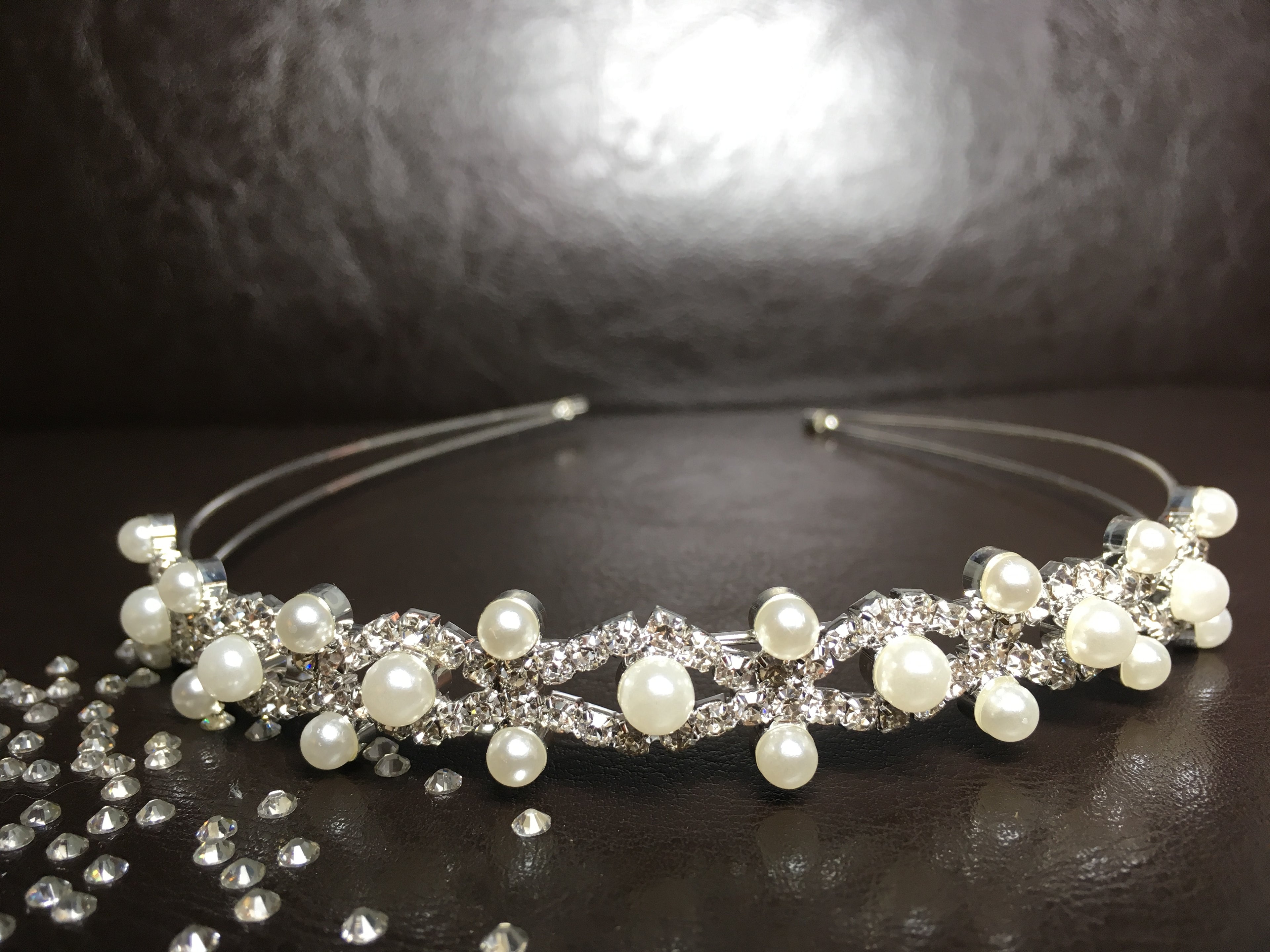 ondego-diadem-perlen-und-strass-vorne-mit-streudeko-auf-braunem-hintergrund